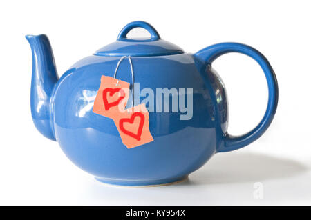 Blue tea pot containing teabags with heart symbols on isolated background Stock Photo