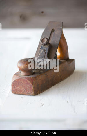 close-up of antique, vintage wooden block plane, against weathered white painted wood background Stock Photo