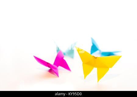 four origami butterflies in yellow, fuchsia, and blue symbolizing springtime, isolated on white background Stock Photo