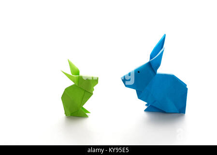 Two colorful origami Easter bunny rabbits made of paper in green and blue, of different sizes, perhaps parent and baby regarding each other, ready for Stock Photo