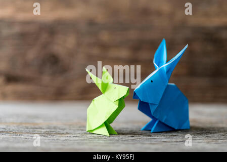 Two colorful origami Easter bunny rabbits made of paper in green and blue, of different sizes, perhaps parent and baby regarding each other, ready for Stock Photo