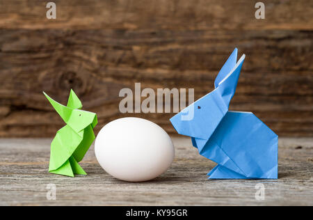 Two colorful origami Easter bunny rabbits made of paper in green and blue, of different sizes, perhaps parent and baby regarding each other over white Stock Photo