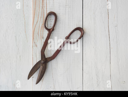 pair of antique, rusted vintage tin snip tool against weathered white painted wood background Stock Photo