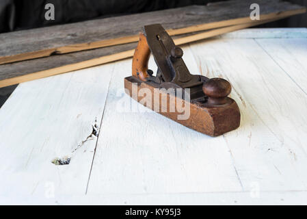 antique, worn, well-used wooden block plane, used by carpenter or cabinet maker for wood working, with old barn wood planks in the background Stock Photo
