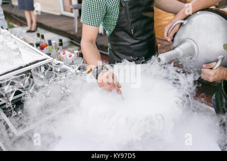 bartenders serve the cocktail in a large bowl with liquid nitrogen. row line of different alcoholic cocktails on a party. wedding day or birthday Stock Photo