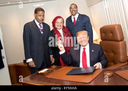 U.S. President Donald Trump hands the pen used to sign the Martin Luther King Jr. National Historical Park Act to Alveda King, center, niece of slain Civil Rights leader aboard Air Force One January 8, 2018 in Atlanta, Georgia. Looking on are Isaac Newton Farris Jr., left, nephew of Dr. King, and Bruce Levell of the National Diversity Coalition for Trump, right. Stock Photo