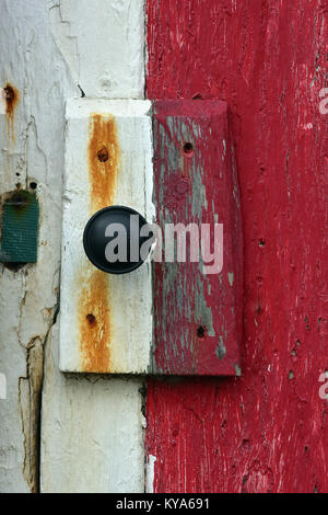 The door handle and makeshift lock on an old painted shed or beach hut held on with rusty or corroded nails. Shabby chic design and style on old hut. Stock Photo