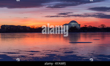 Colors are cast in the sky at sunrise over a frozen Tidal Basin and Jefferson Memorial in Washington, D.C. Stock Photo