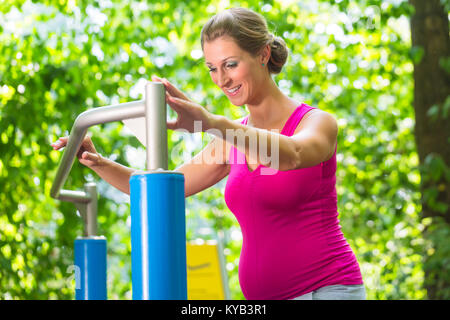 Pregnant woman having fitness workout at climbing frame Stock Photo
