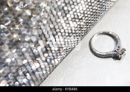 Wedding ring with silver handbag on white table. Stock Photo