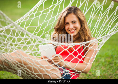Girl lying in hammock and using digital tablet Stock Photo