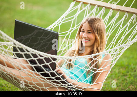 Girl lying in hammock and using laptop Stock Photo