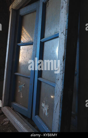 Blue wooden old frames with dirty glasses on a dark background, in glass reflects a glare from the window. Stock Photo