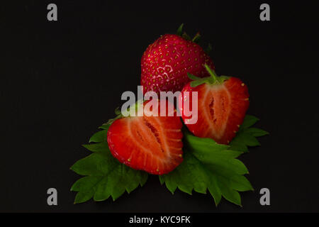 ripe cut in strawberries on a black textural background Stock Photo