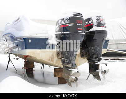 Pleasure boat with two Suzuki outboard motors, stored on dry land at a marina during winter in Norway. Stock Photo
