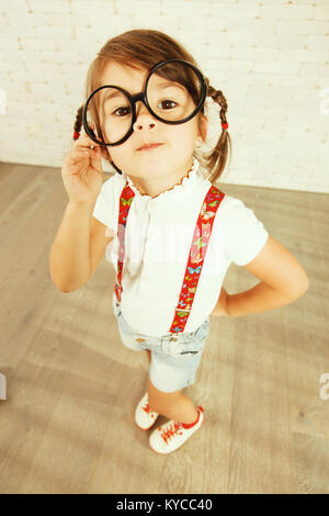 Little nerd girl looking at camera with big eyes wearing glasses. Stock Photo