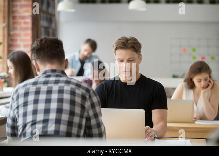 Serious businessman focused on laptop, man using pc sitting at shared office desk, busy developer programmer concentrated on work in co-working space, Stock Photo