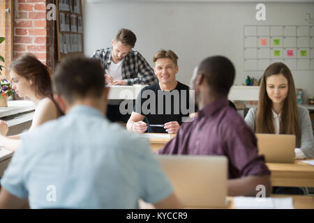 African-american and caucasian colleagues talking at work in coworking space, diverse employees discussing project task communicating at workplace, fr Stock Photo