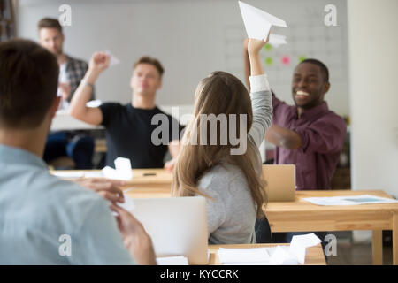 Startup concept, happy young motivated multi-ethnic business team launching paper planes together in coworking space, diverse businesspeople group hav Stock Photo