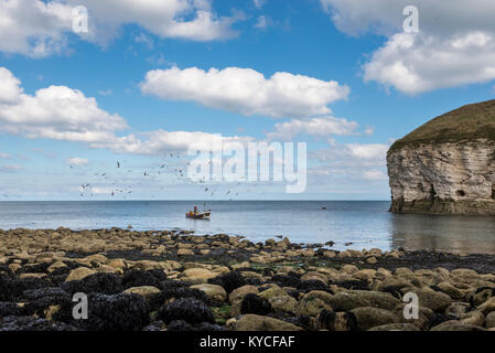Small traditional fishing boat surrounded by sea birds at North Landing, Flamborough, North Yorkshire, England. Stock Photo