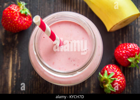 Strawberry and banana smoothie on rustic wooden background. Healthy breakfast or snack. Banana and strawberry smoothie in glass jar. Stock Photo