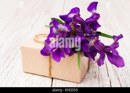 bouquet of purple irises flowers and gift closeup on a light wooden background Stock Photo