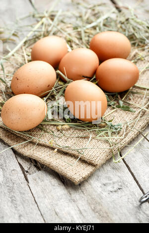 fresh eggs for Easter, eggs lie on burlap, on a wooden background Stock Photo