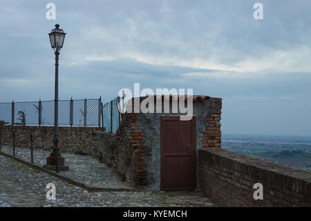 External wooden door in an old guard post of a surrounding wall with street lights Stock Photo