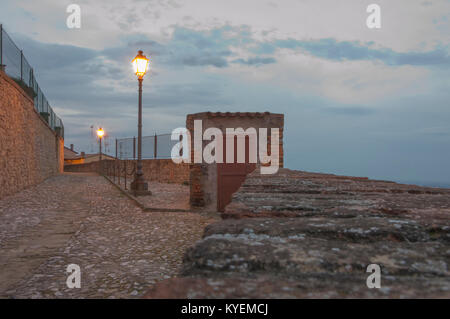 External wooden door in an old guard post of a surrounding wall with street lights Stock Photo