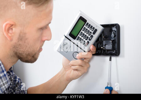 Young Male Technician Installing Security System Using Screwdriver Stock Photo