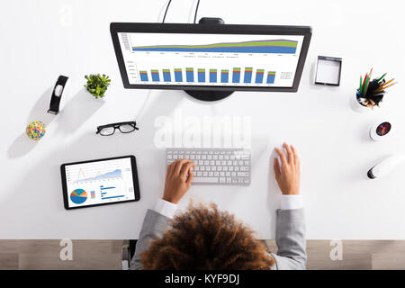 Elevated View Of A Businesswoman Analyzing Graph On Computer At Workplace Stock Photo