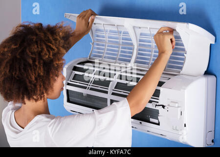 Close-up Of A Young Woman Checking Air Conditioner At Home Stock Photo