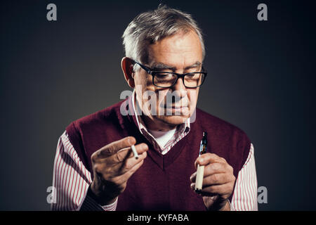 Portrait of senior man who is decided to quit smoking cigarettes in favor of electronic cigarette. Stock Photo