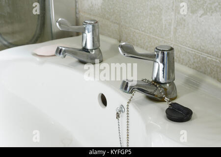 Close up detail of a domestic hand basin in white ceramic with silver taps with levers Stock Photo