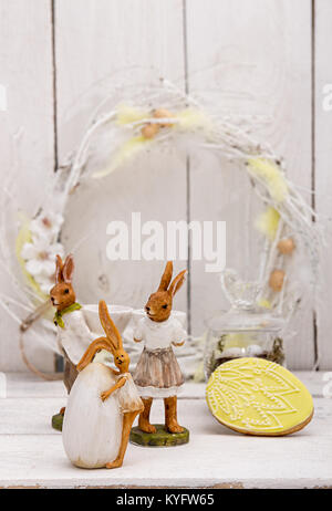 Happy Easter decoration for greeting card. Easter bunnies, wreath,  gingerbread Easter cookies in shape of Easter eggs on white background. Vintage st Stock Photo
