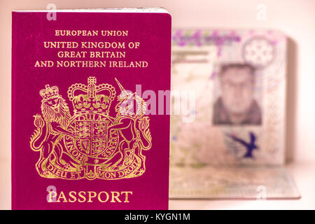 UK passports with one opened showing a blurred photo page. Each passport states: European Union United Kingdom of Great Britain and Northern Ireland. Stock Photo