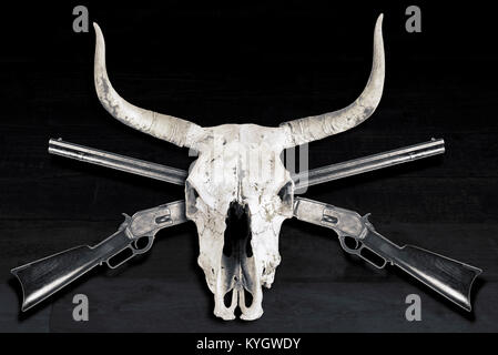Antique cowboy lever action rifle and cow skulls in black and white. Stock Photo