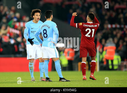 Manchester City's Leroy Sane (left) and Manchester City's Ilkay Gundogan (centre) appear dejected as Liverpool's Alex Oxlade-Chamberlain celebrates after the final whistle during the Premier League match at Anfield, Liverpool. Stock Photo