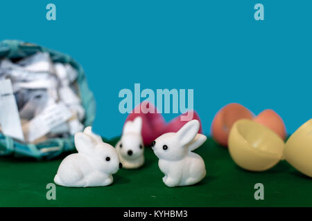 Easter basket filled with plastic eggs rolls over and little white bunnies hatch from cracked colorful plastic eggs Stock Photo