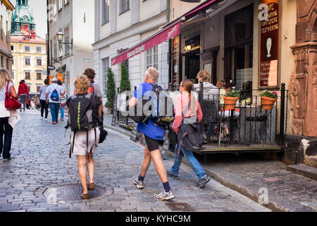 Stockholm busy street in historic Gamla Stan, or Old Town, popular with tourists. Crowds walking on cobblestone streets, eating in sidewalk cafes. Stock Photo