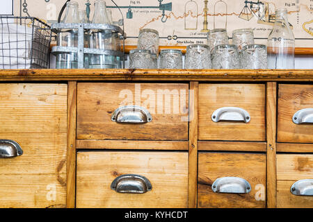 Swedish antique pine sideboard cabinet with drawers with metal pulls. Used in a dining setting with drinking glasses and napkins on top. Stock Photo