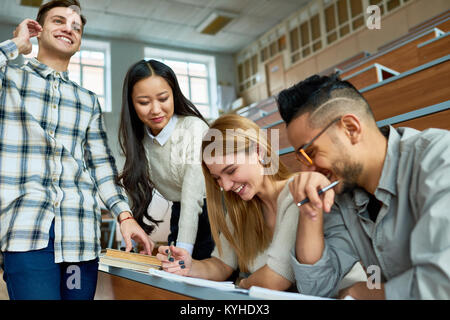 Multi-ethnic group of students having fun  and laughing  in lecture hall of modern college while enjoying classes, focus on beautiful young woman Stock Photo