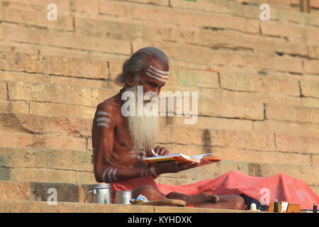 Religious man reads a book at Manmandir ghat on Ganges river in Varanasi India. Stock Photo