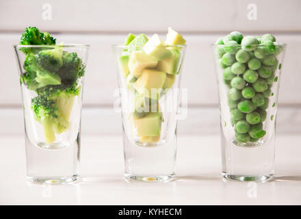 closeup of assortment of green cut vegetables in shot glass on white background. Stock Photo