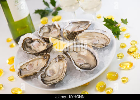 Oysters on ice and with a piece of lemon and wine bottle and glass Stock Photo