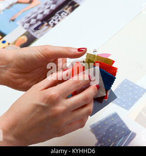 A womans hand holding a selection of coloured fabric swatches Stock Photo