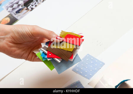 A womans hand holding a selection of coloured fabric swatches Stock Photo