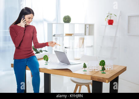 Smart engineer sitting on the table while talking on the phone Stock Photo
