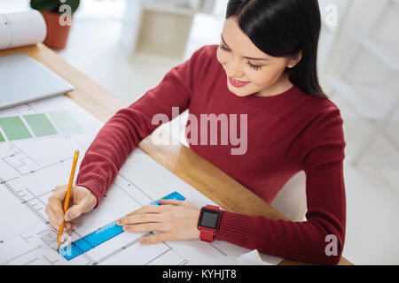 Responsible engineer sitting and drawing the lines on her scheme Stock Photo