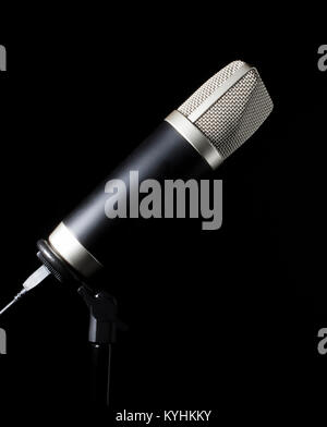 Black background behind a microphone with wire mesh head Stock Photo